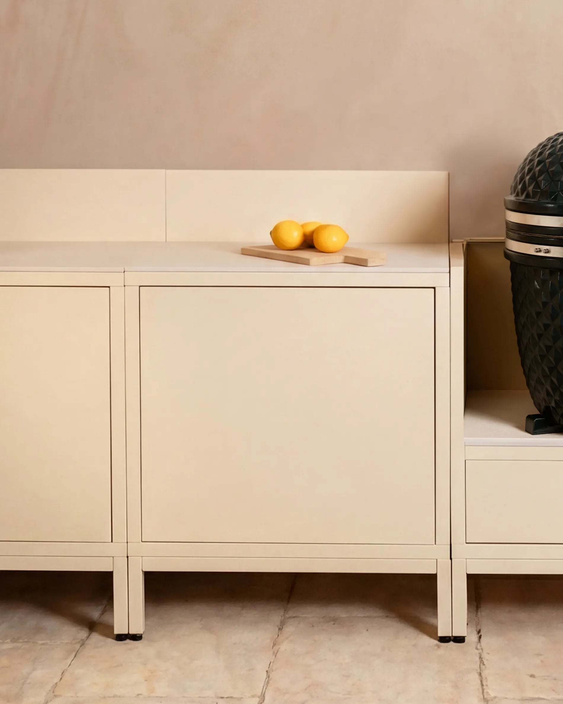 Módulos beige crema Classic PILOTIS en cocina exterior, con kamado y limones sobre la tabla