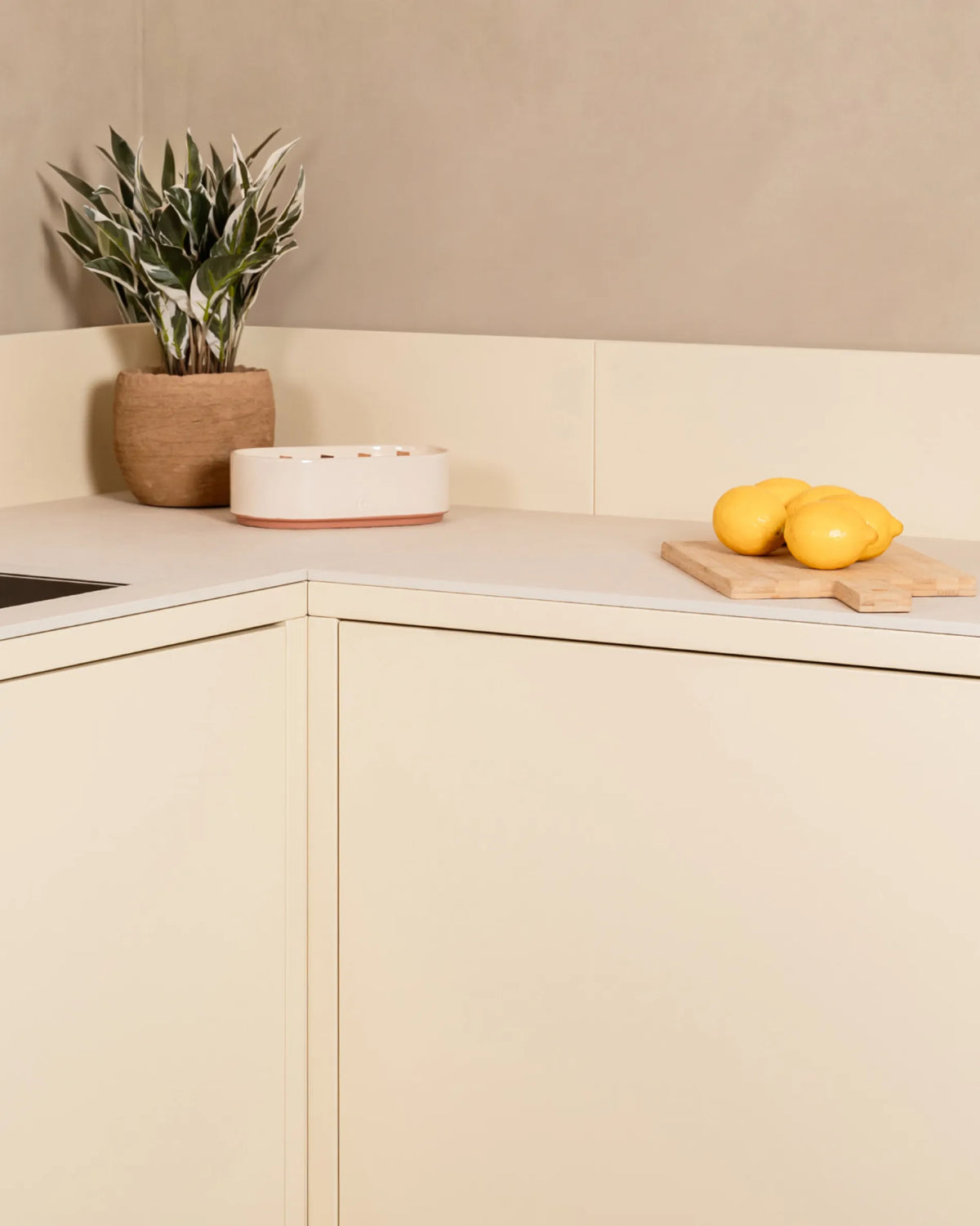 Módulo de esquina beige crema PILOTIS para cocina exterior, con planta y limones sobre la encimera