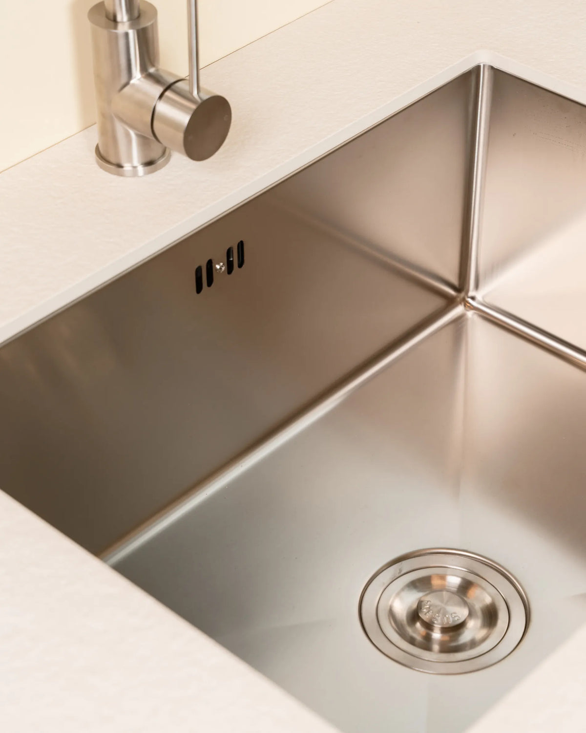 Fregadero de acero inoxidable del módulo de fregadero PILOTIS integrado en encimera beige crema, vista en primer plano