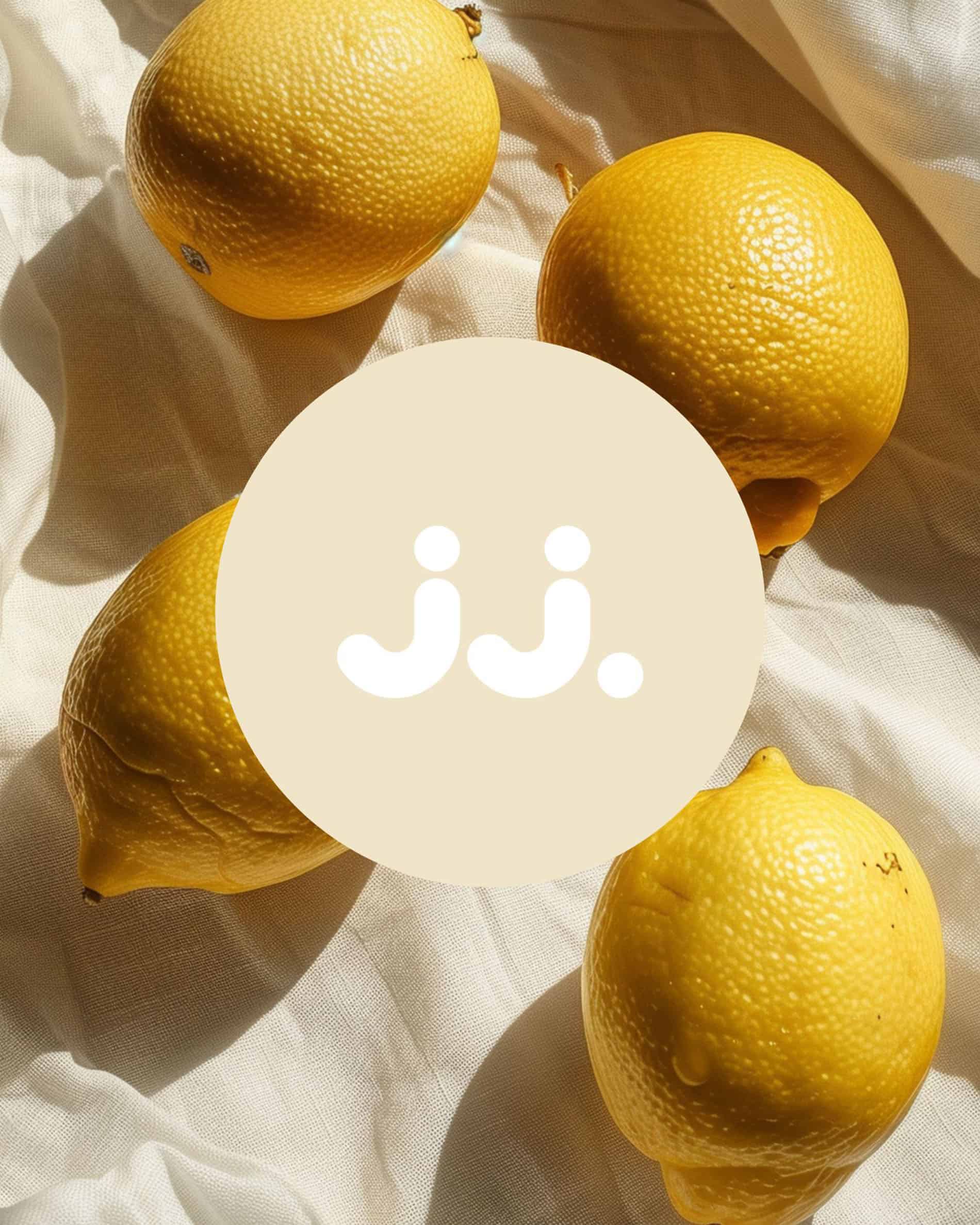 Limón amarillo sobre tela clara con logo jj., evocando la fragancia de Citronela & Limón.