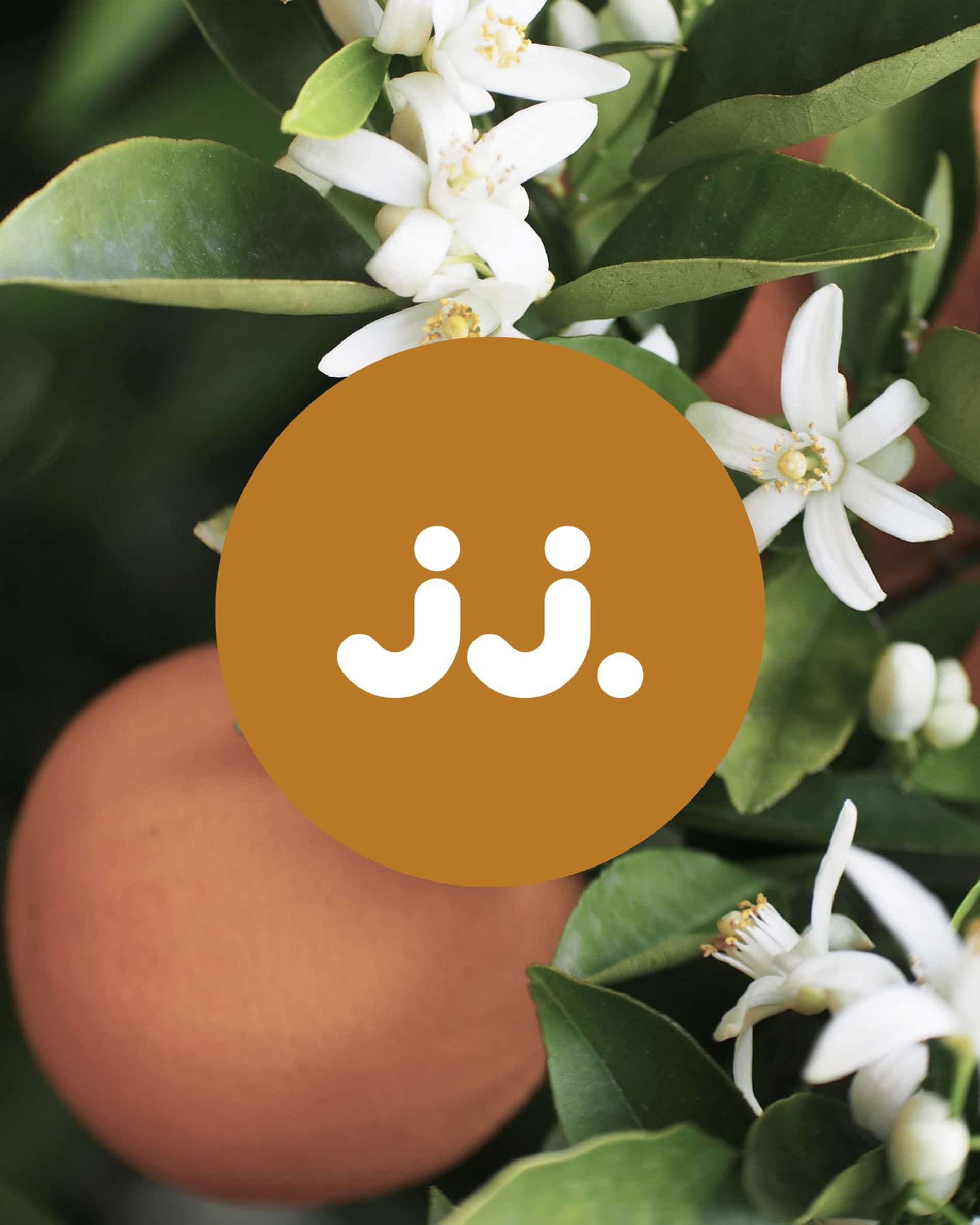 Flores de azahar y frutas anaranjadas con el logo jj., para la fragancia Citronela & Flor de azahar.