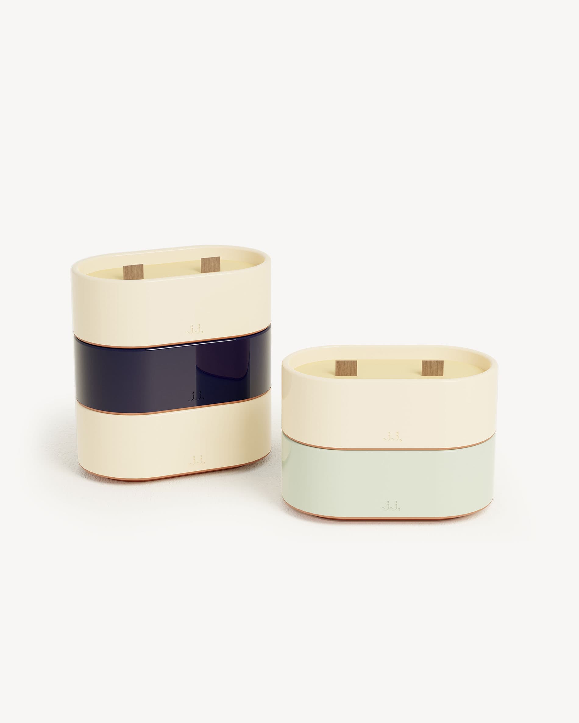 Bougie Totem S de cerámica bicolor beige marfil y azul marino, perfumada con citronela y notas de limón y sal marina, presentada junto a una versión verde agua con eucalipto.