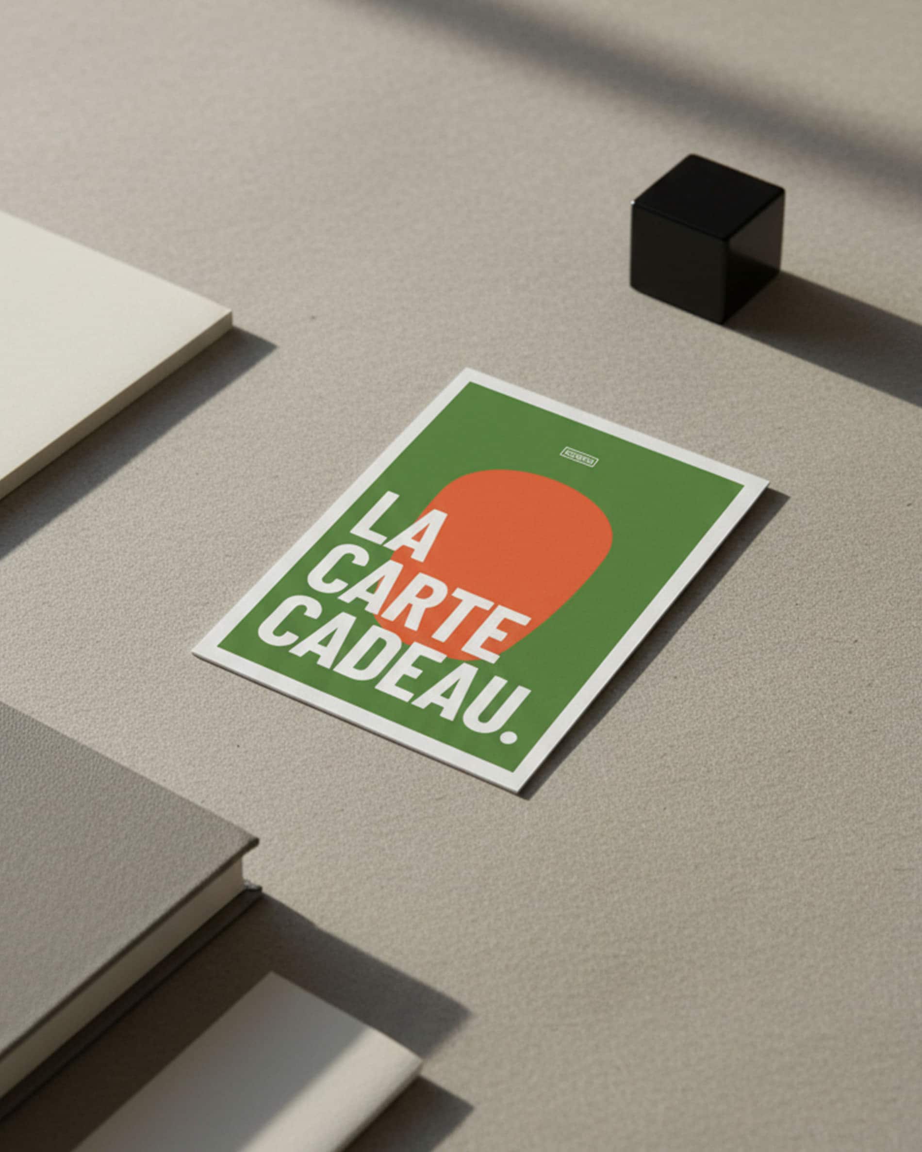 Tarjeta regalo Kokko sobre una superficie mineral, diseño gráfico en verde y naranja con el texto «la tarjeta regalo».