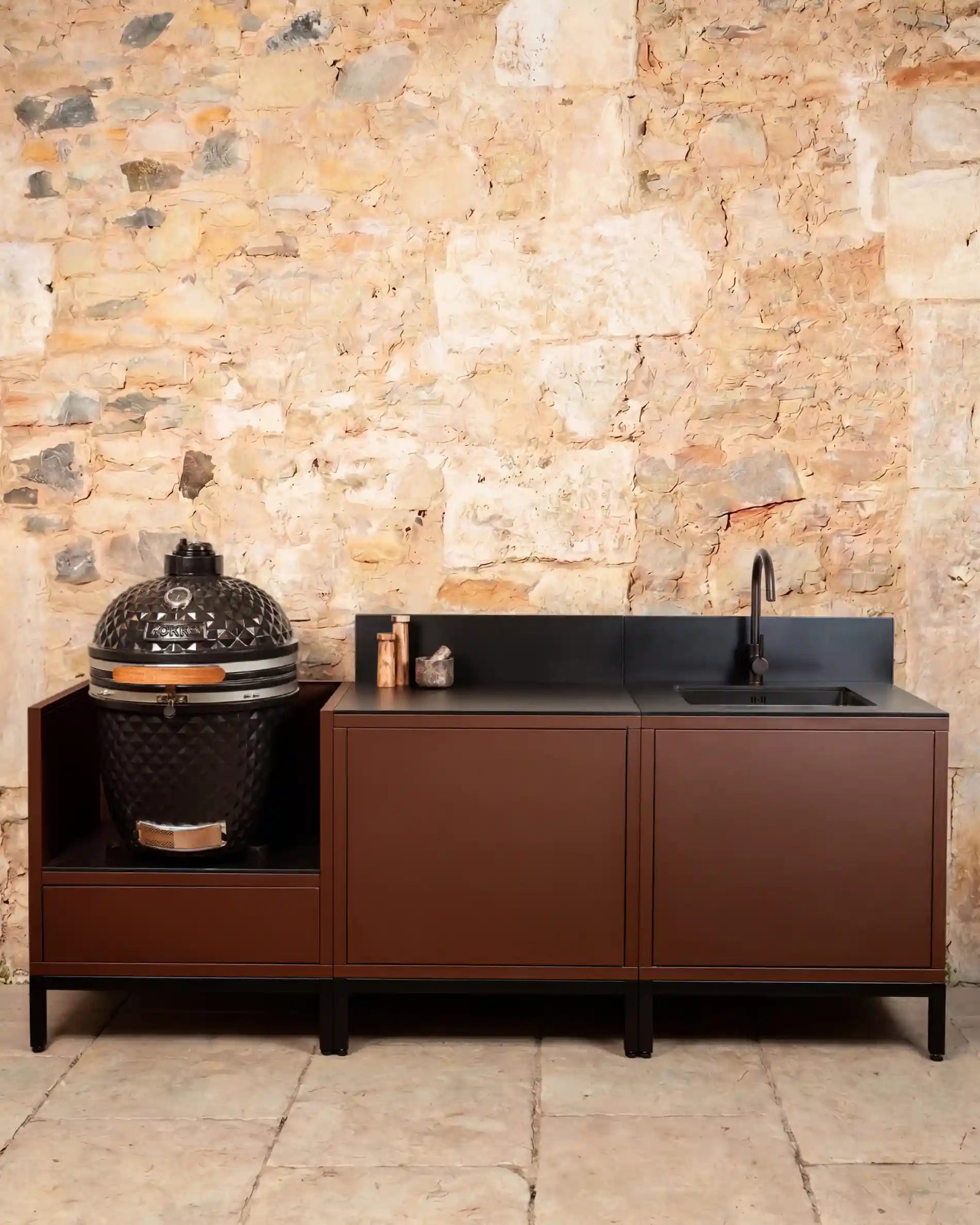Cocina exterior Kokko Pilotis rust con encimera negra y kamado