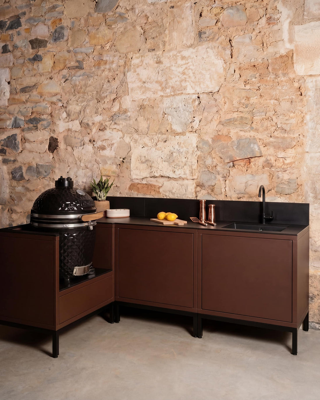 Cocina exterior Kokko Pilotis en esquina color rust con fregadero y kamado integrado