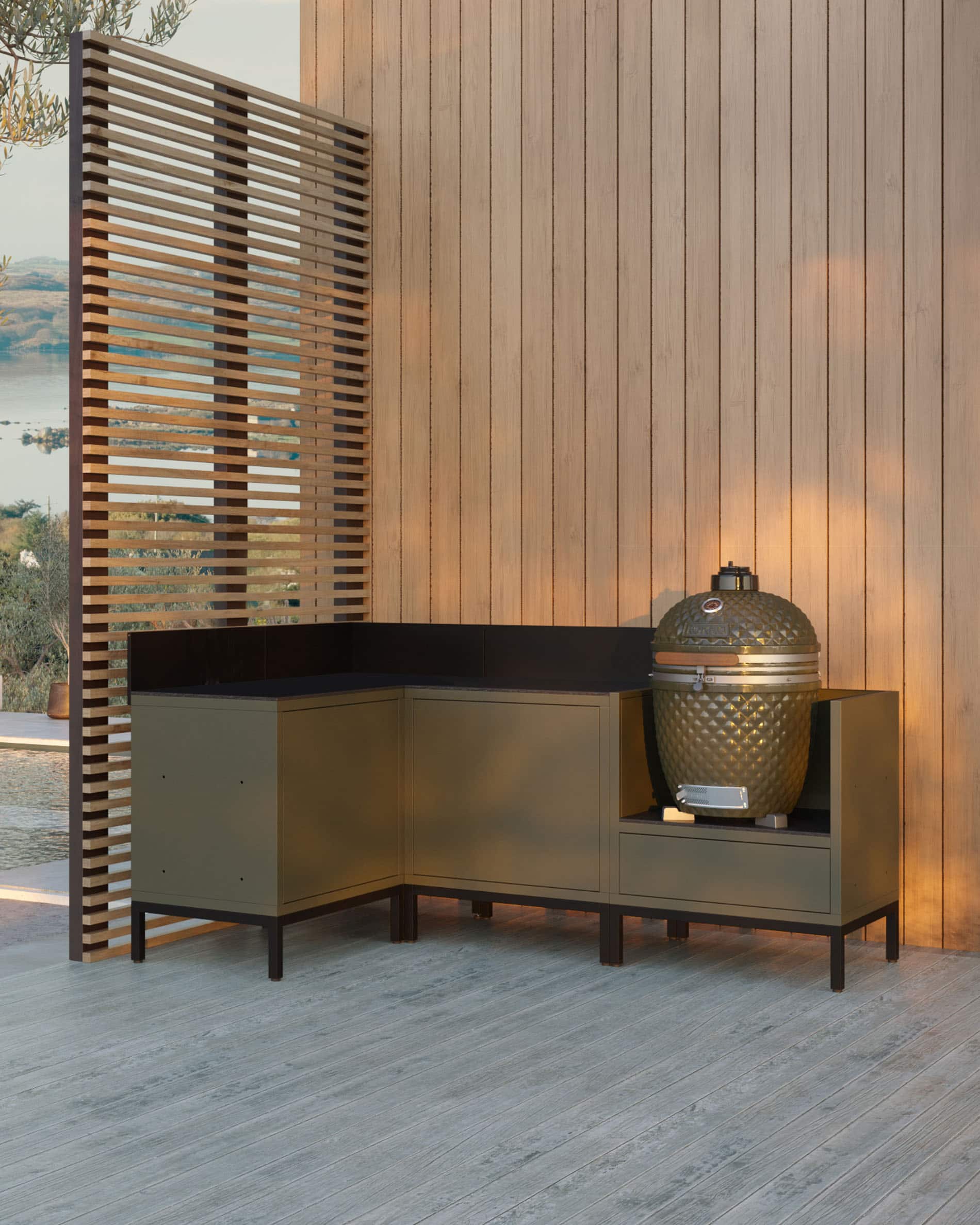 Módulo de cocina en esquina para kamado, conjunto de muebles en color verde oliva con fregadero integrado, encimera oscura y panel trasero a juego, kamado instalado en el módulo lateral derecho, estructura sobre patas negras.