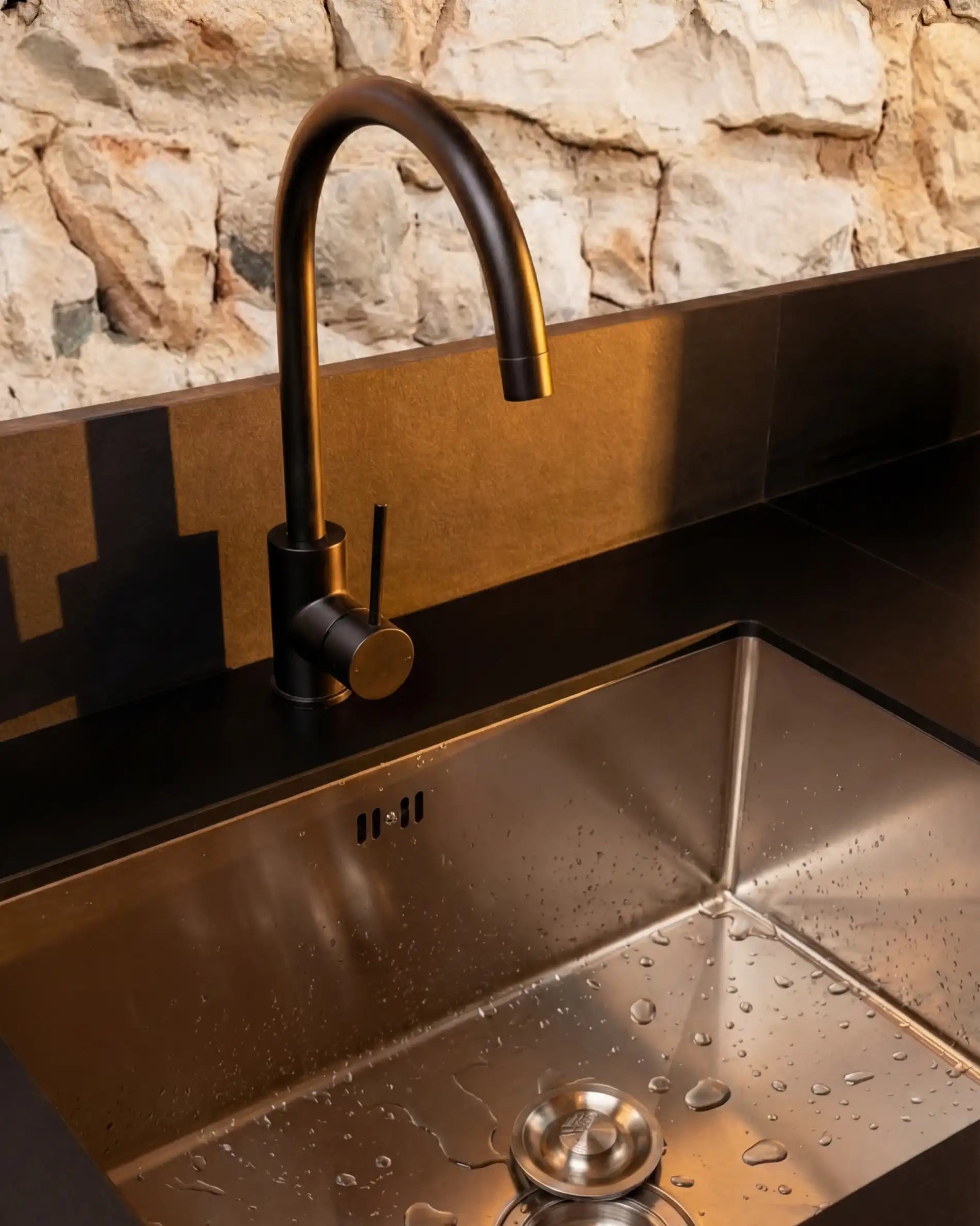 Détail évier inox avec robinet noir sur cuisine extérieure Kokko