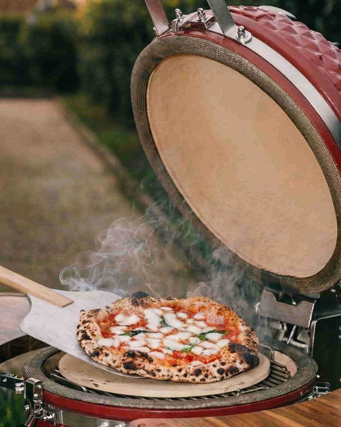 Pizza colocada sobre una piedra refractaria en un kamado Kokko abierto, cocción al carbón vegetal.