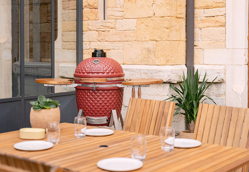 Zona de cocción de un kamado Kokko con parrilla y accesorios en uso.