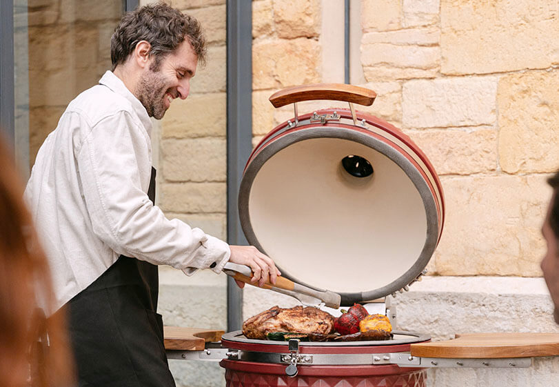 Experto de Kokko utilizando un kamado rojo óxido al aire libre para mostrar las mejores prácticas de cocción.