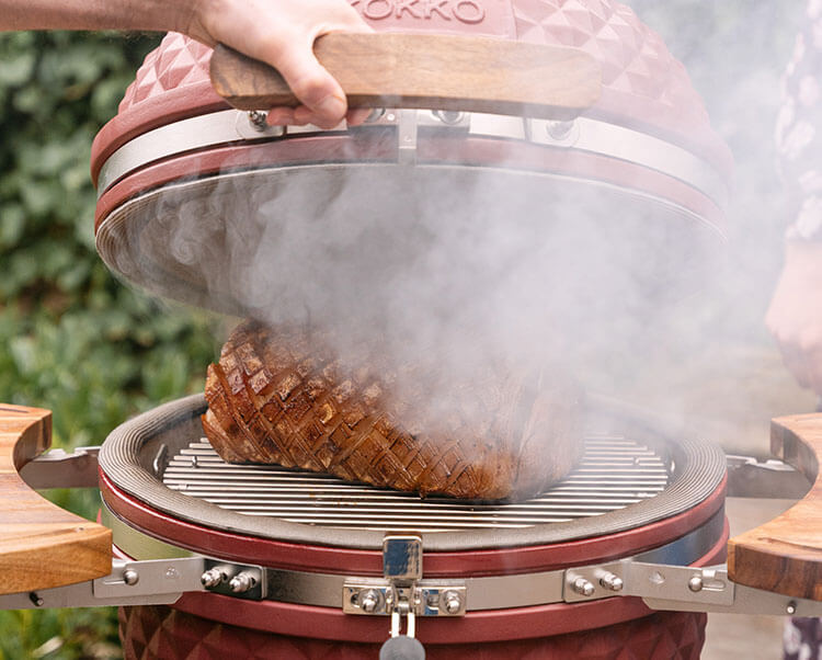 Kamado Kokko utilisé pour le fumage à chaud, montrant la cuisson des aliments avec production de fumée pour un arôme intense.