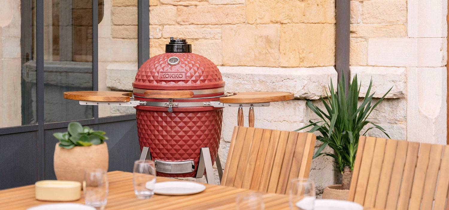 Kamado Kokko rouge oxyde installé en extérieur, illustrant l’univers et l’histoire de la marque.