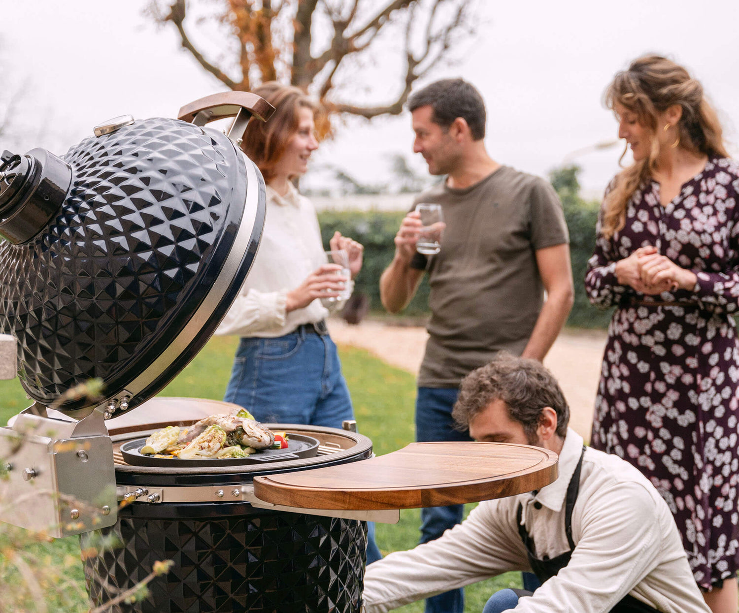 Kamado Kokko nouvelle édition en situation d’utilisation, avec des aliments en cours de cuisson pour illustrer la convivialité et la performance du barbecue.