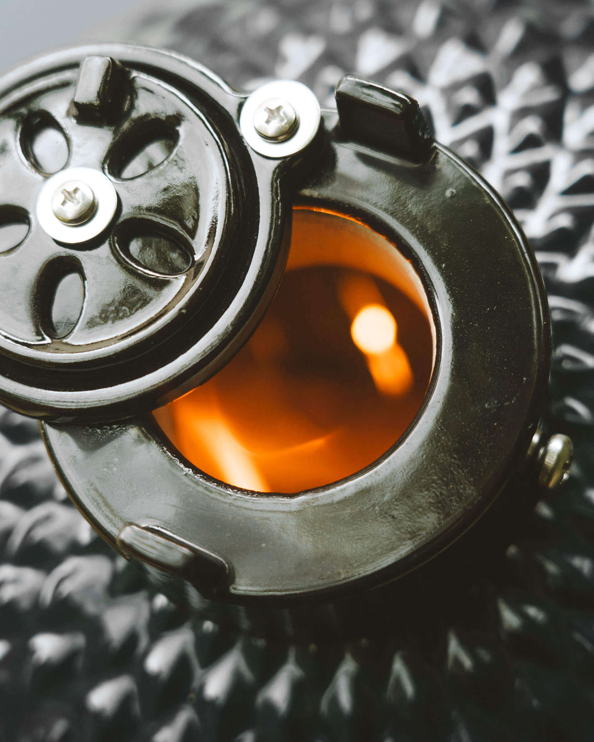Vista de cerca del sistema de ventilación superior de un kamado Kokko, con apertura circular y brasas incandescentes visibles.