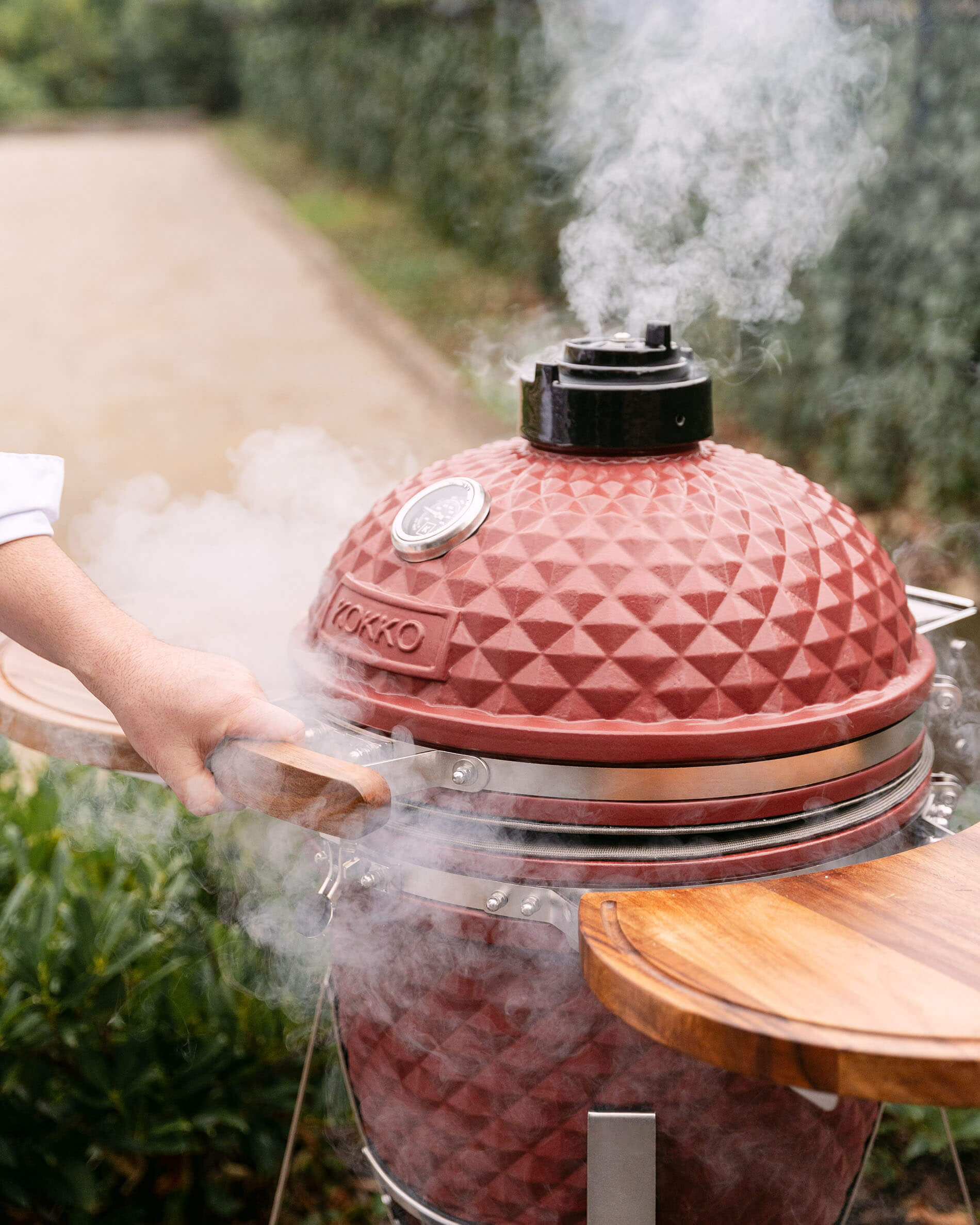 Kamado Kokko L de 18 pulgadas en cerámica rojo óxido con humo de cocción.