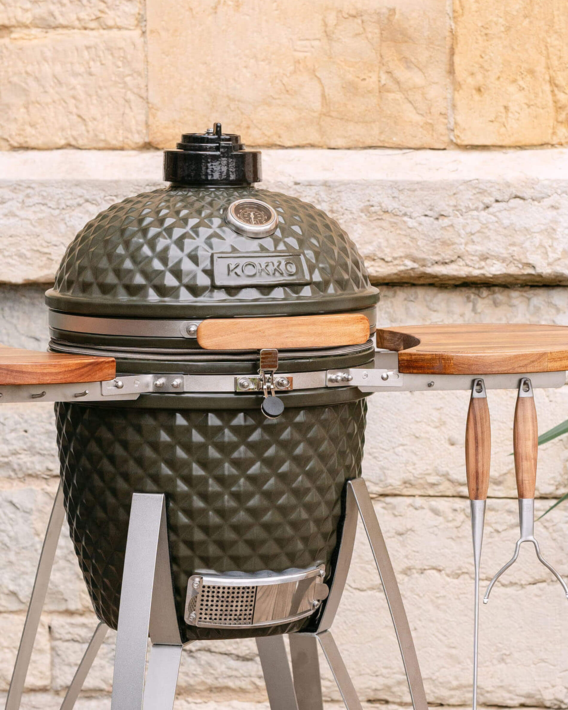 Kamado Kokko de 18 pulgadas en color verde oliva, presentado solo en exterior.