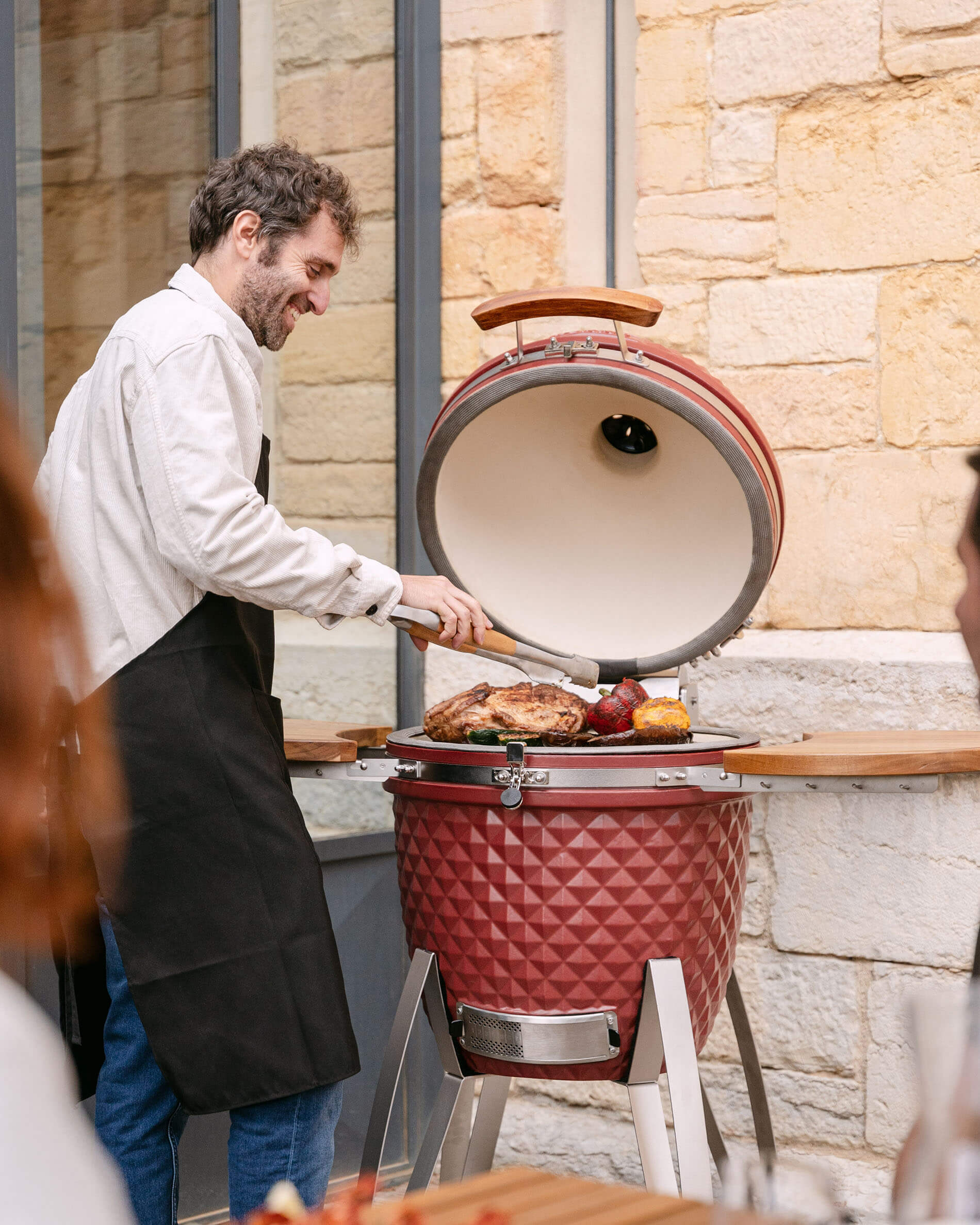 Kamado Kokko de cerámica rojo óxido en uso durante la cocción.