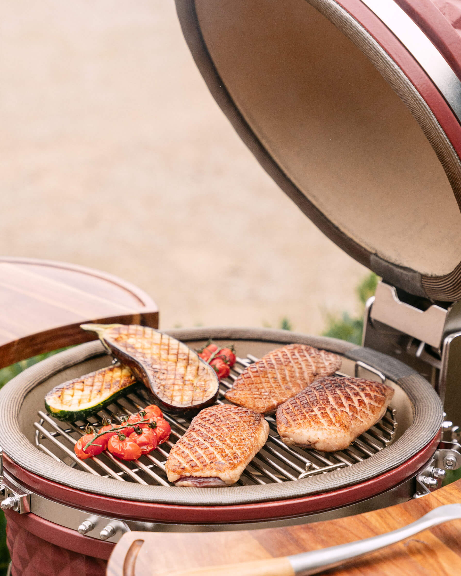 Kamado Kokko L de 18 pulgadas en plena cocción con carnes y verduras sobre la parrilla.