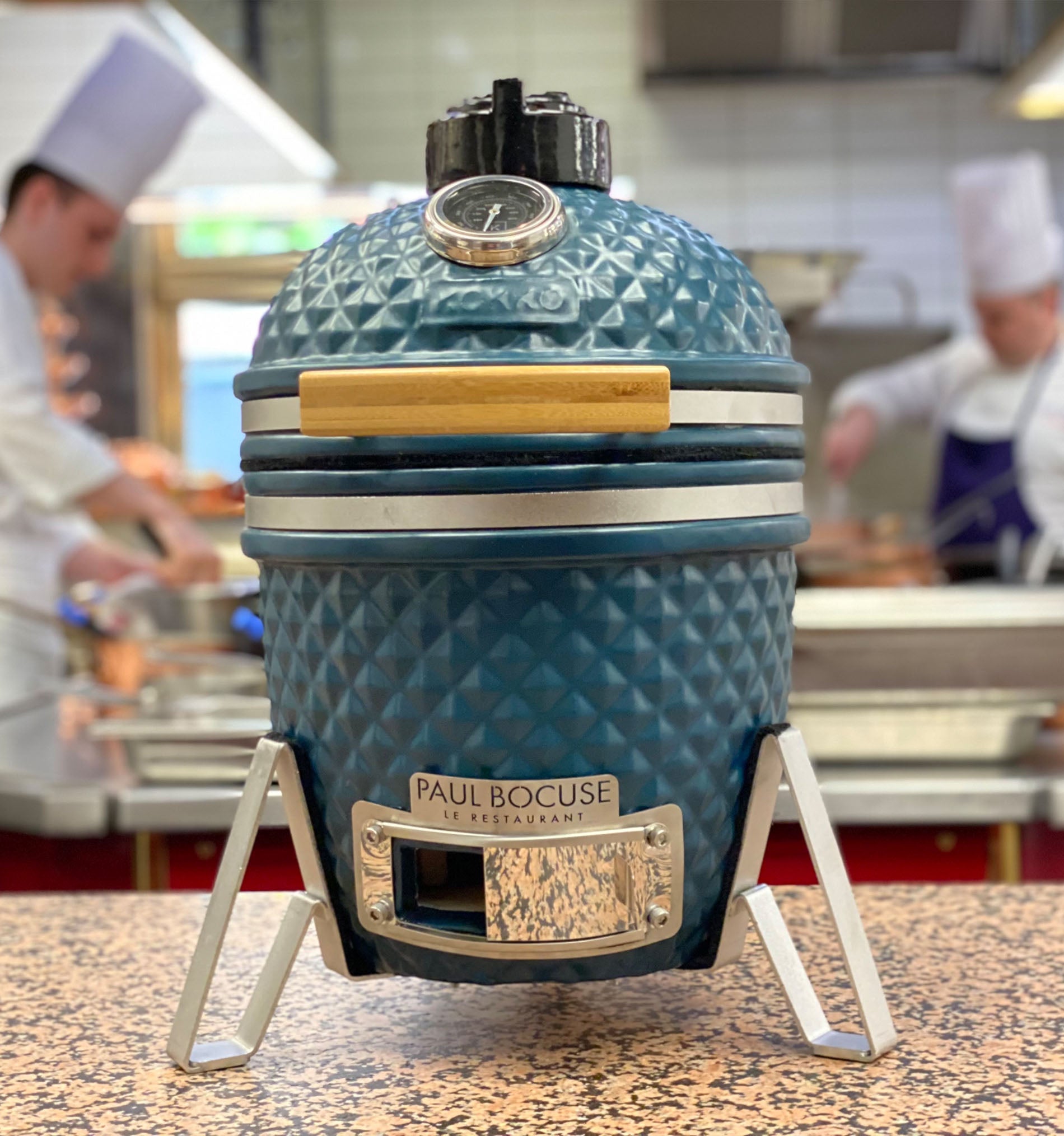 Kamado Kokko azul océano instalado frente a un restaurante gastronómico Paul Bocuse.