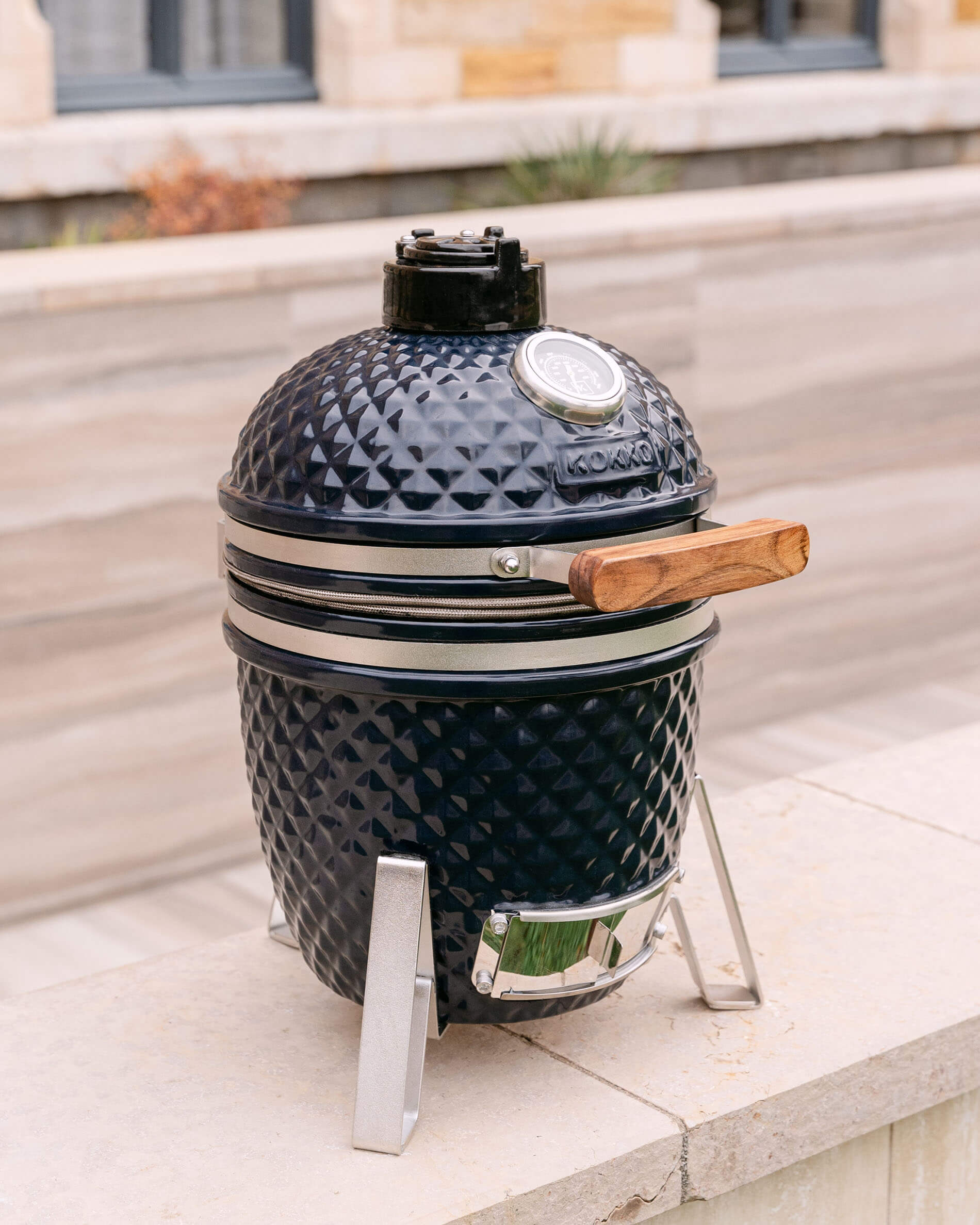 Kamado Little Kokko 13 azul marino presentado en su soporte en exterior.