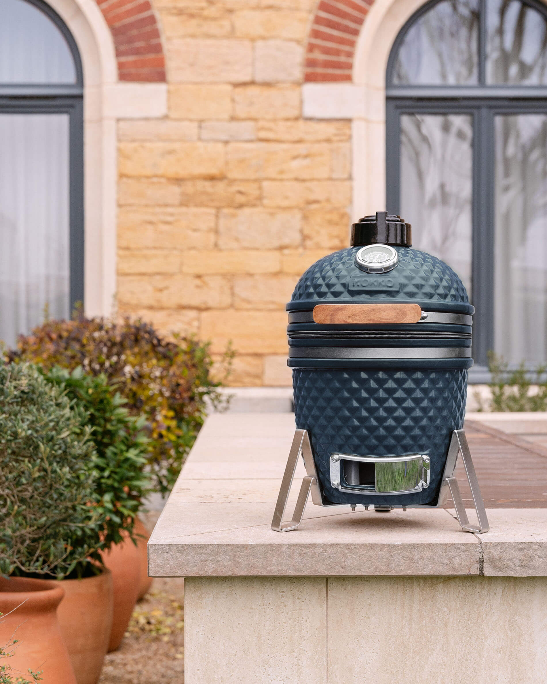 Kamado Little Kokko 13 de cerámica azul océano, instalado en exterior.