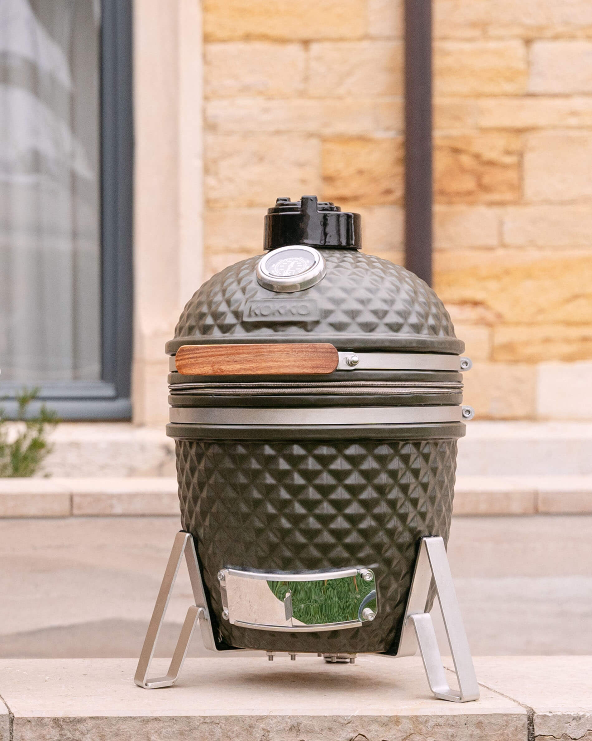Kamado Little Kokko 13 de cerámica en verde oliva sobre su soporte.