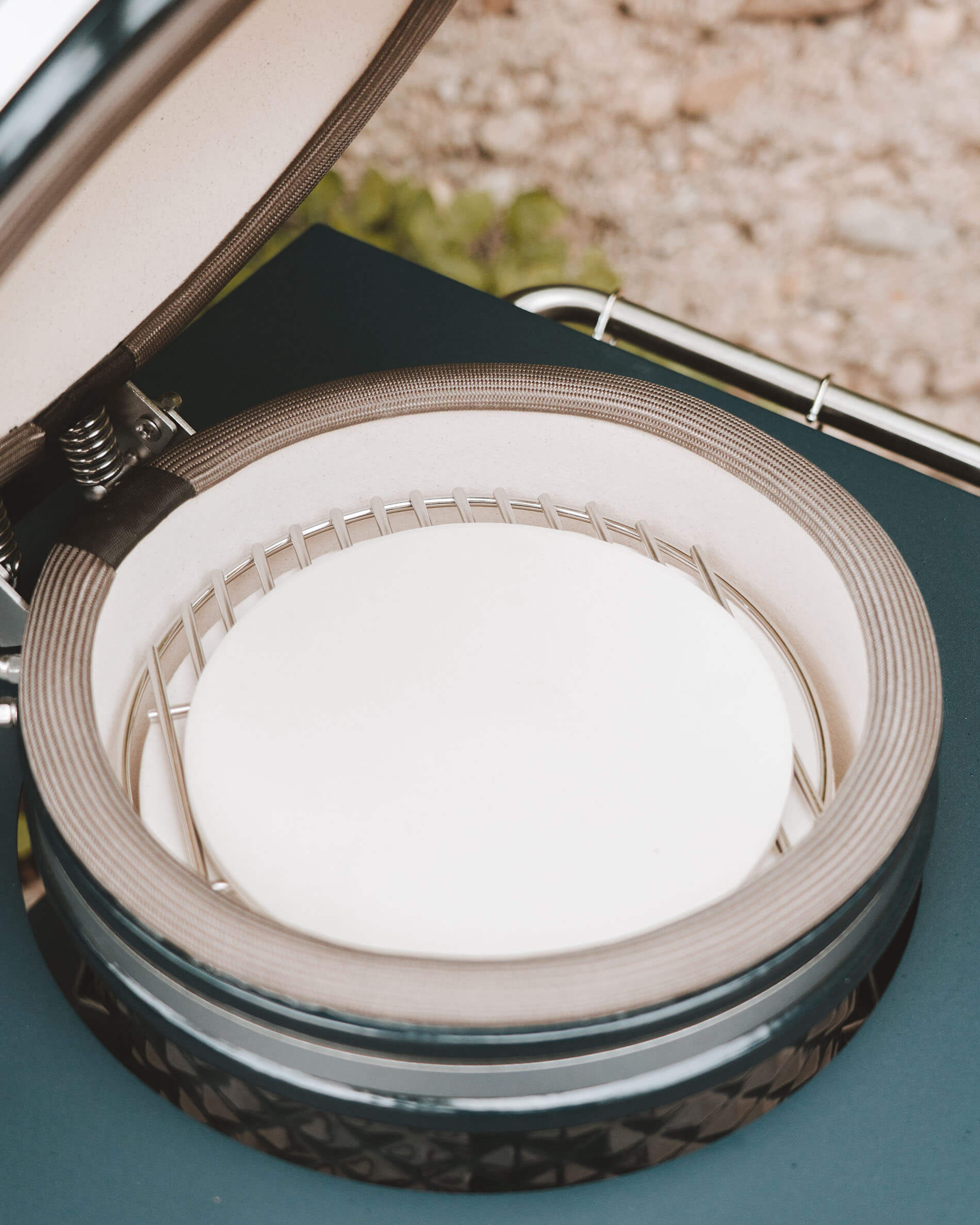 Interior del kamado Kokko con piedra para pizza colocada sobre el soporte de cocción, vista detallada de la cerámica y la junta de sellado.