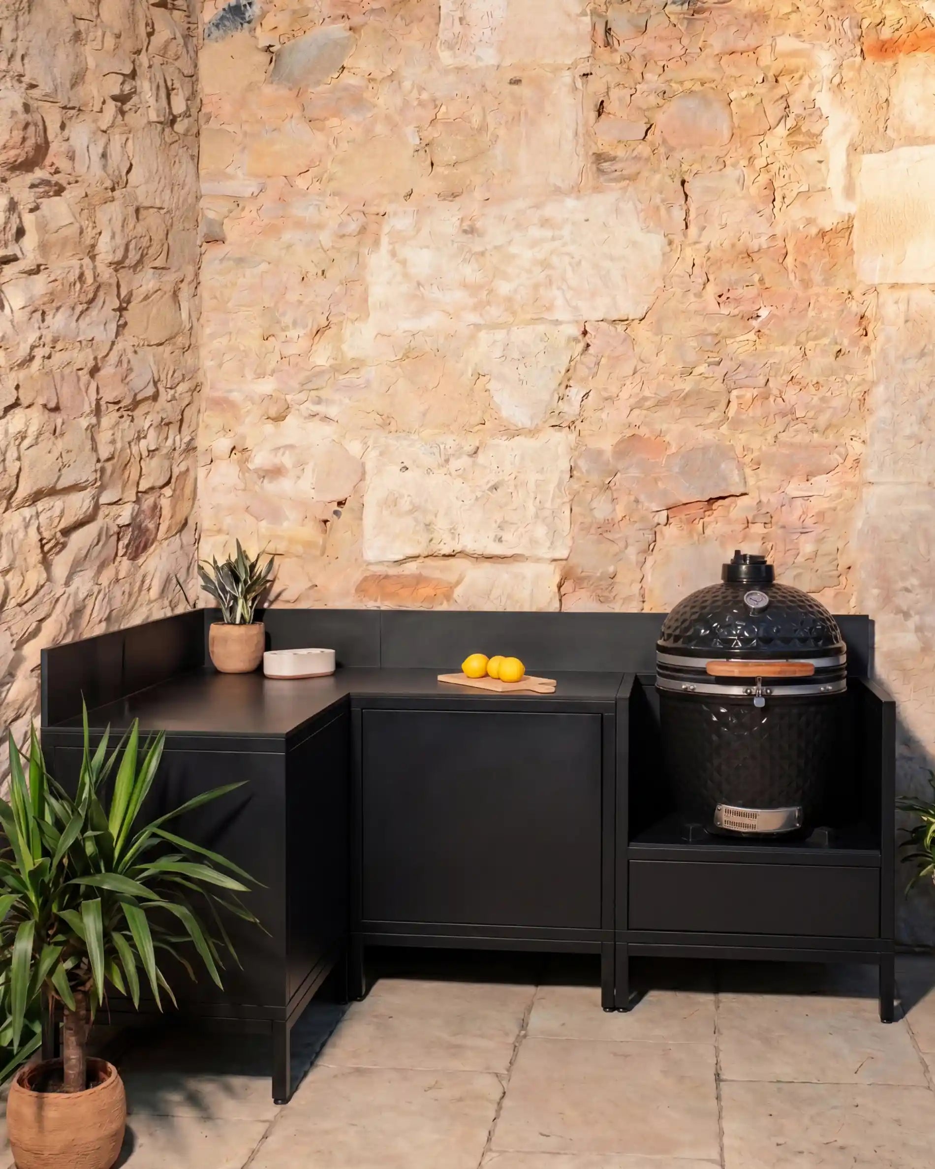 Cocina exterior Kokko negra en esquina con kamado y módulos de almacenamiento