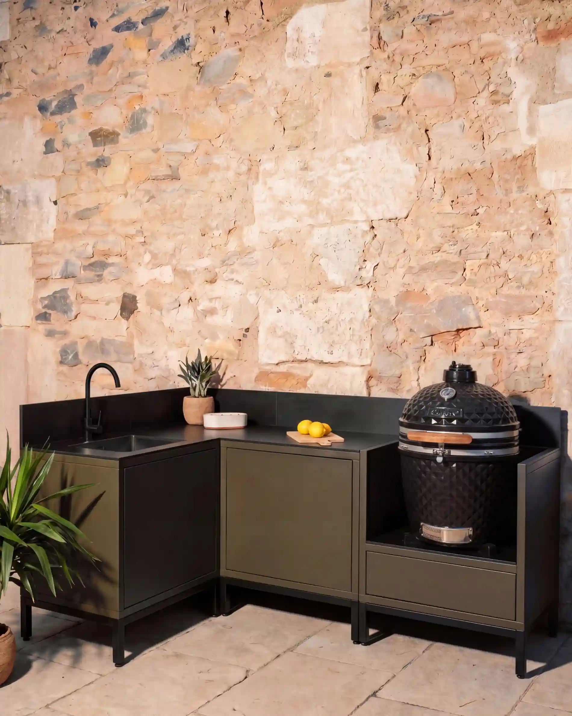 Cocina exterior Kokko olive en esquina con fregadero negro y kamado
