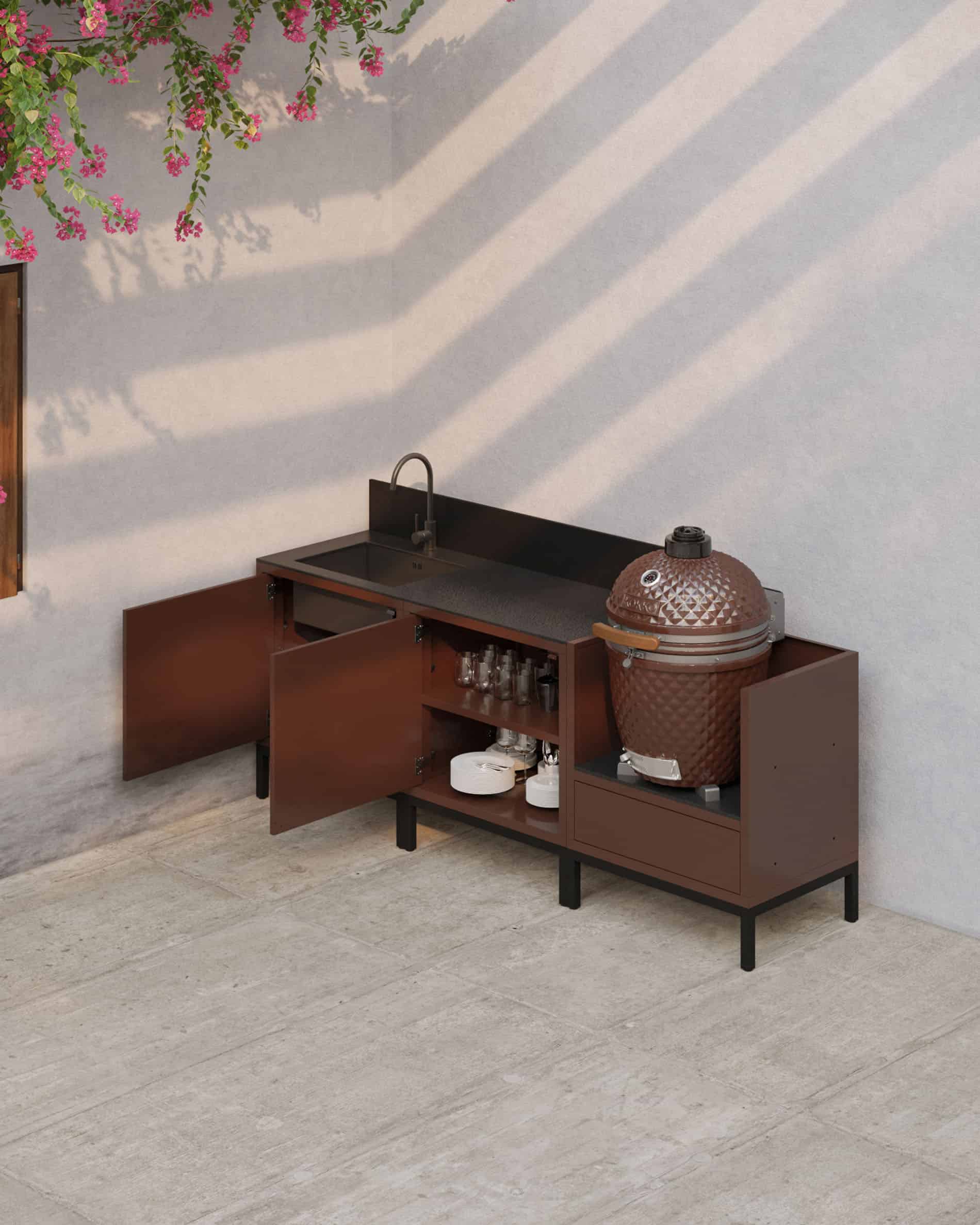 Cocina sobre pilotes en acabado óxido con puertas abiertas, encimera oscura, espacios de almacenamiento interiores visibles y módulo kamado integrado para una cocina exterior funcional.