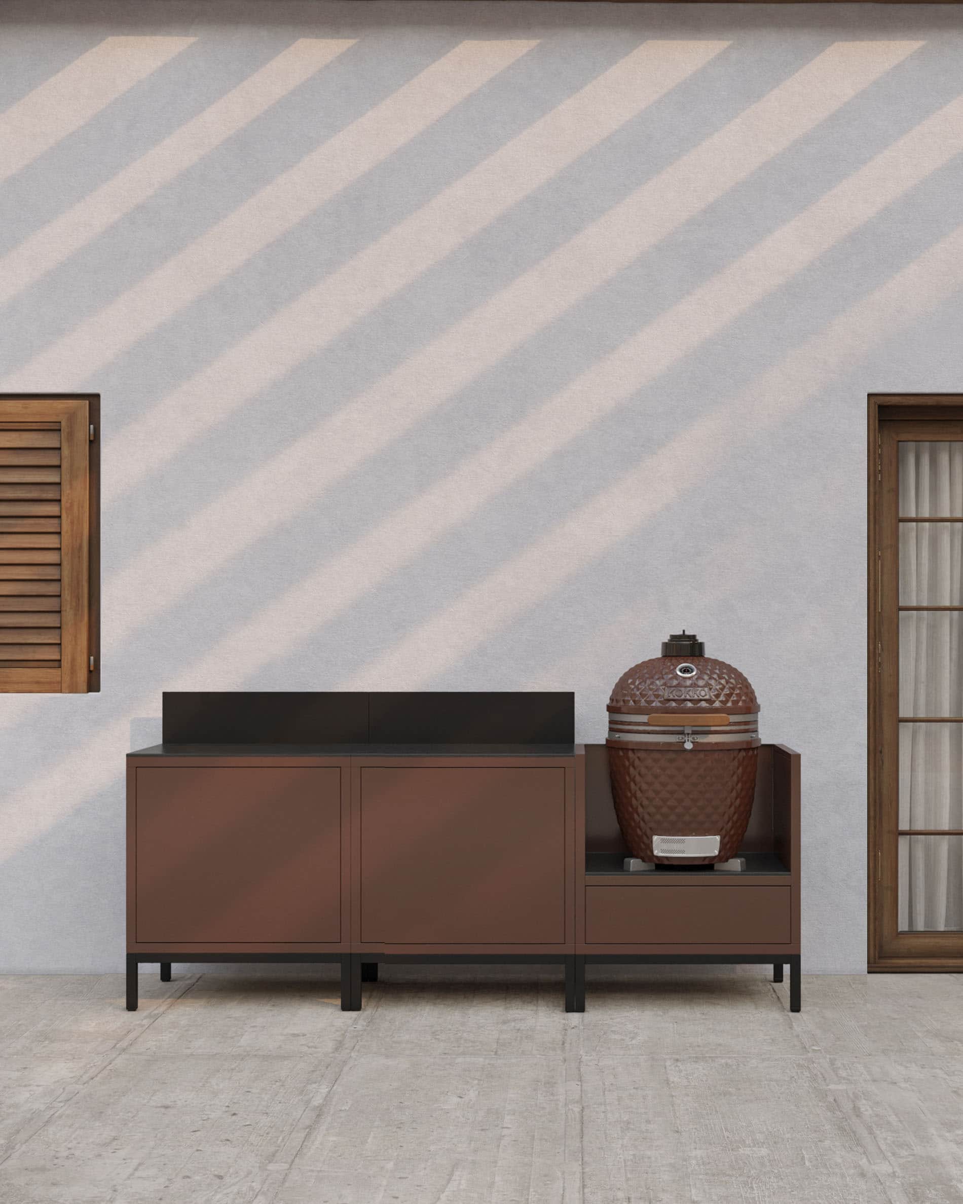 Cocina exterior sobre pilotes en color óxido, con encimera oscura, almacenaje cerrado y módulo específico para integrar un kamado.