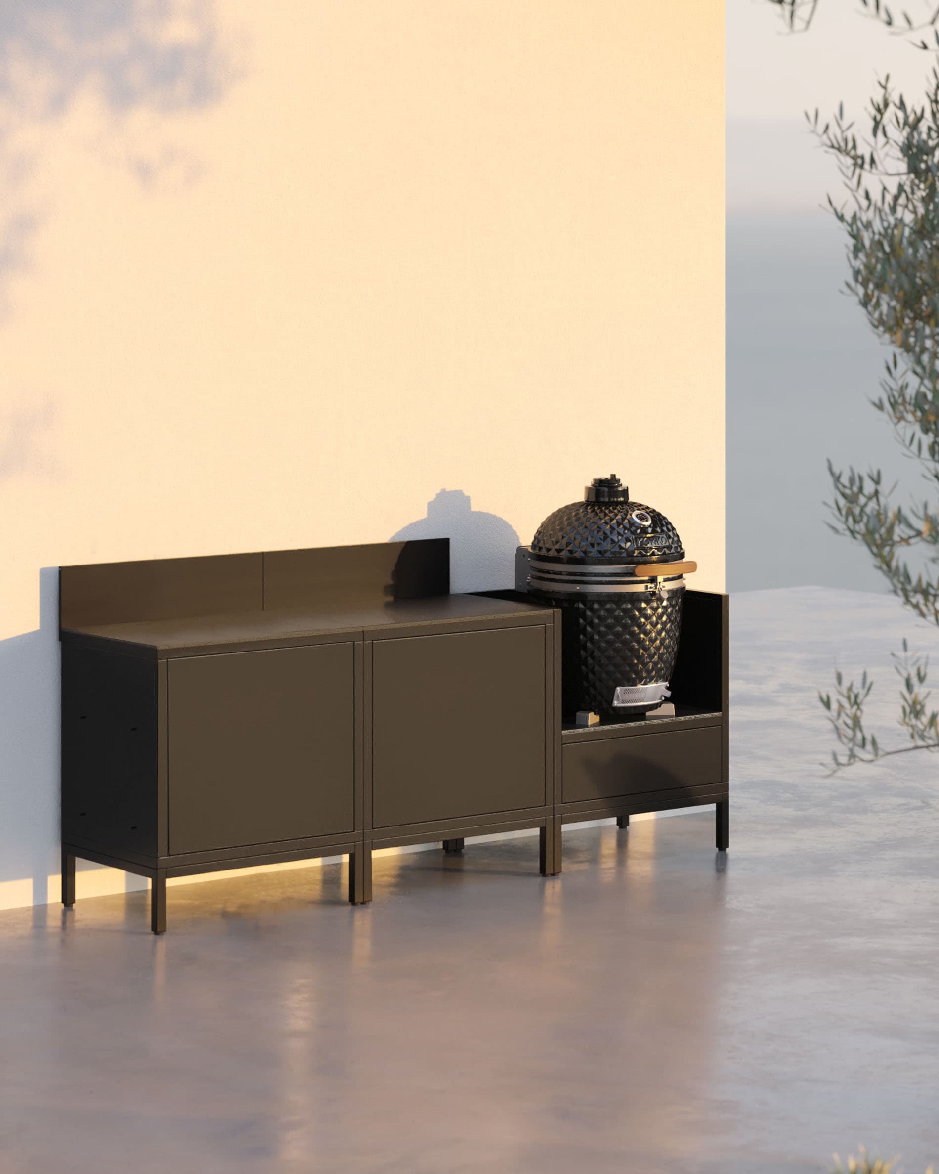 Cocina exterior sobre pilotis con 3 módulos, kamado, mueble negro, encimera oscura y almacenaje cerrado.