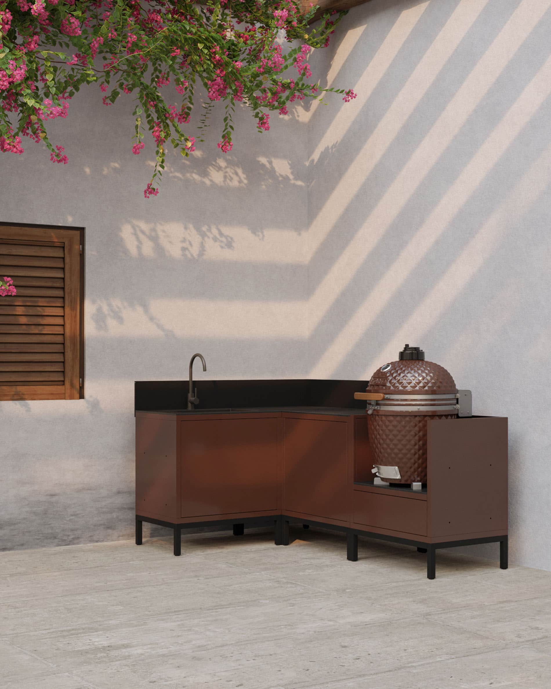 Cocina de exterior en esquina sobre pilotis, color óxido, con encimera oscura, almacenaje cerrado y módulo específico para integrar un kamado.