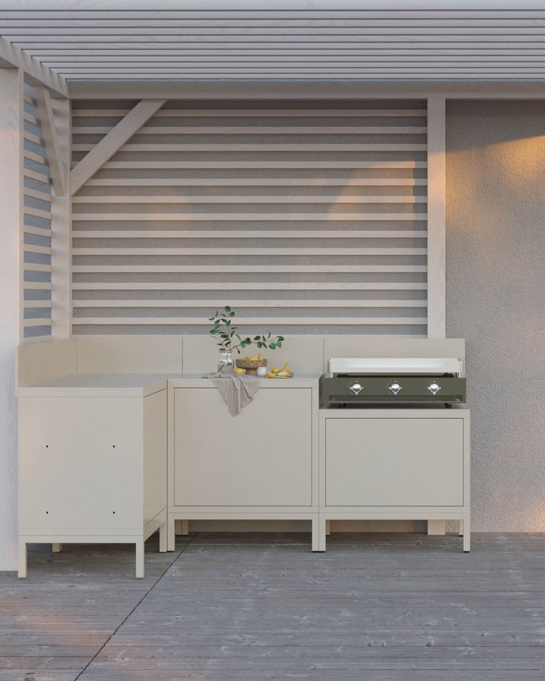 Cocina exterior sobre pilotes con plancha integrada, muebles en color crema, almacenaje cerrado y encimera clara, instalada bajo una pérgola.