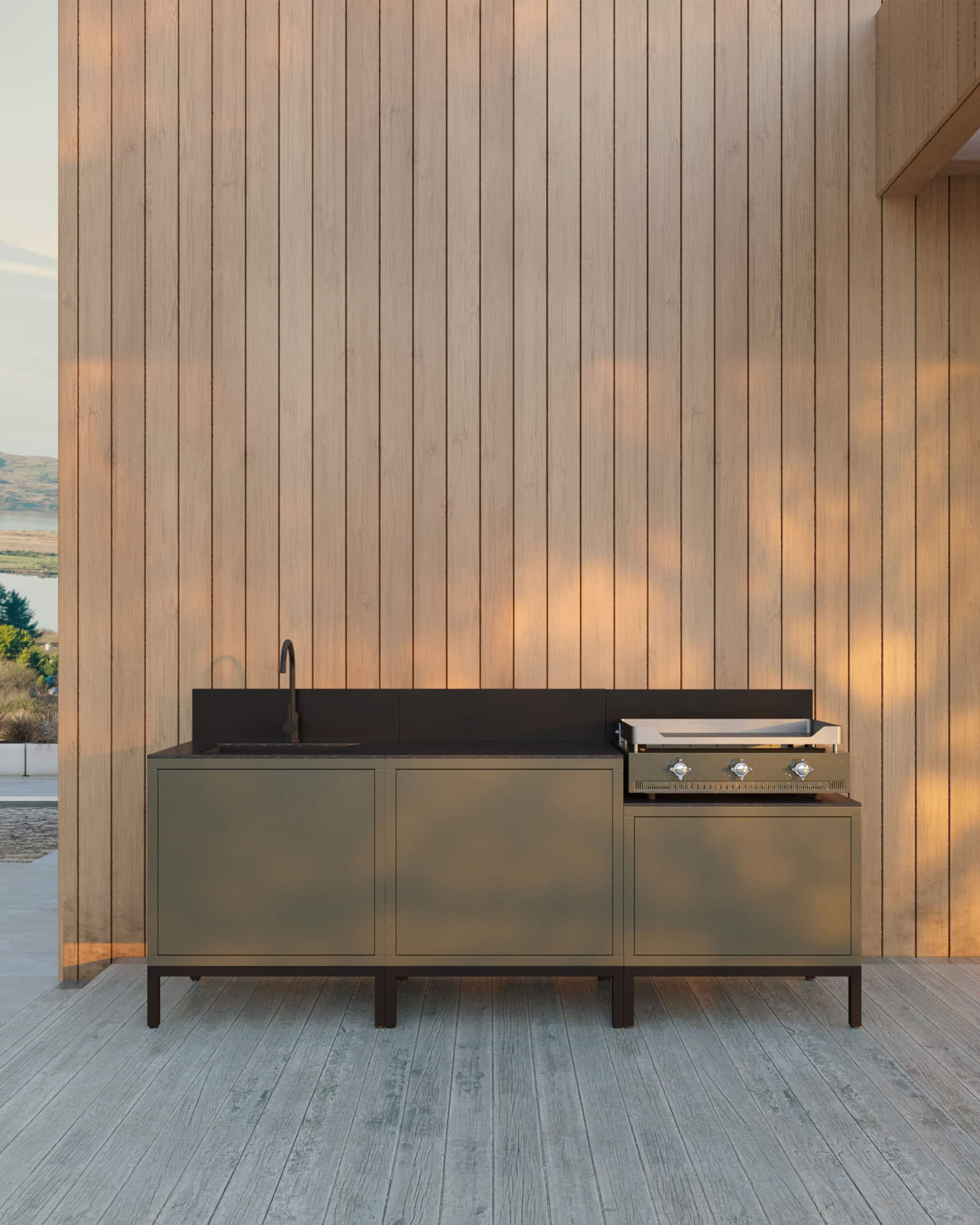 Cocina exterior Kokko con plancha integrada, mueble de almacenamiento verde, fregadero y encimera negra, instalada en una terraza de madera.