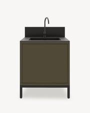 Módulo de cocina pilotis con fregadero integrado, mueble en color verde oliva con almacenamiento cerrado, encimera oscura y panel protector integrado.