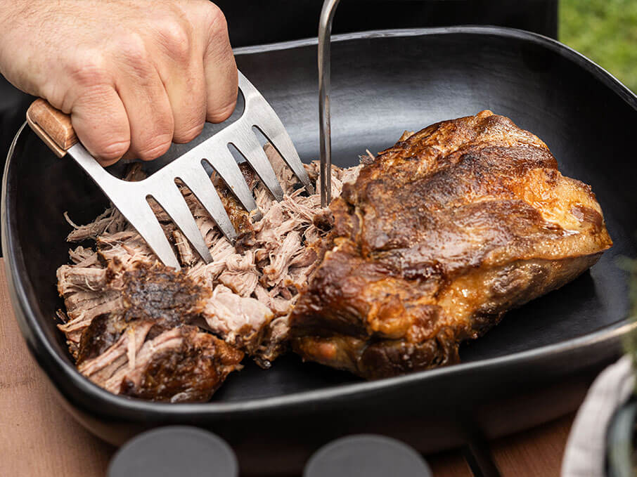 Cerdo ahumado desmenuzado en kamado Kokko, mostrando la textura de la carne tras una cocción lenta.