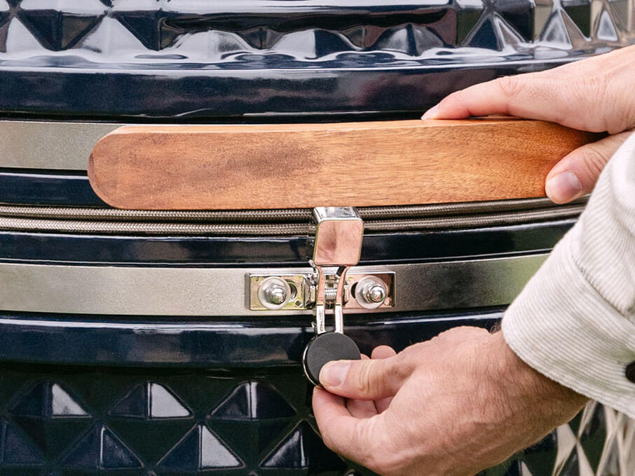 Gros plan sur le loquet de sécurité du kamado Kokko nouvelle édition, assurant le maintien du couvercle lors de l’ouverture et de la fermeture.