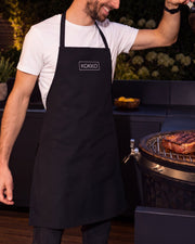 Delantal Kokko negro llevado delante de un kamado Kokko
