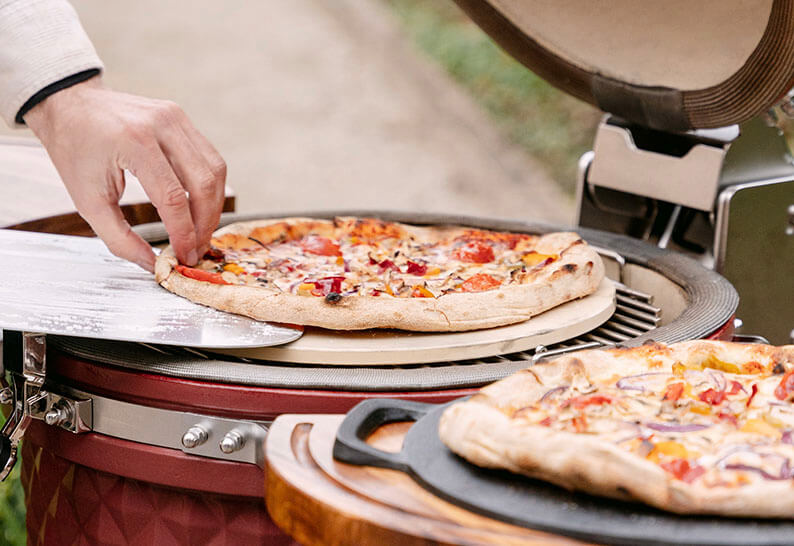 Pizzas cocinándose en un kamado Kokko, mostrando la cocción indirecta sobre piedra refractaria.